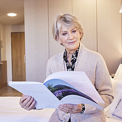 Eine Medical Park Patientin liest sich eine Broschüre zur Beantragung einer geriatrischen Reha durch.